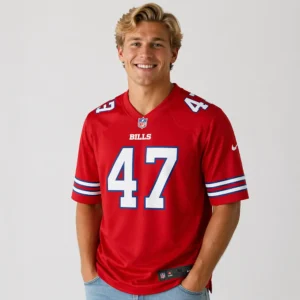 A smiling male model wears the red Buffalo Bills #47 jersey, posed with his hands in his jeans pockets against a light grey background.