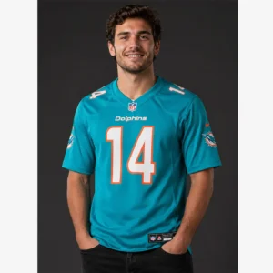Smiling young man wearing an aqua Miami Dolphins Quinn Ewers #14 jersey against a dark grey background.